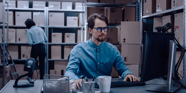 man at desk on computer with coffee